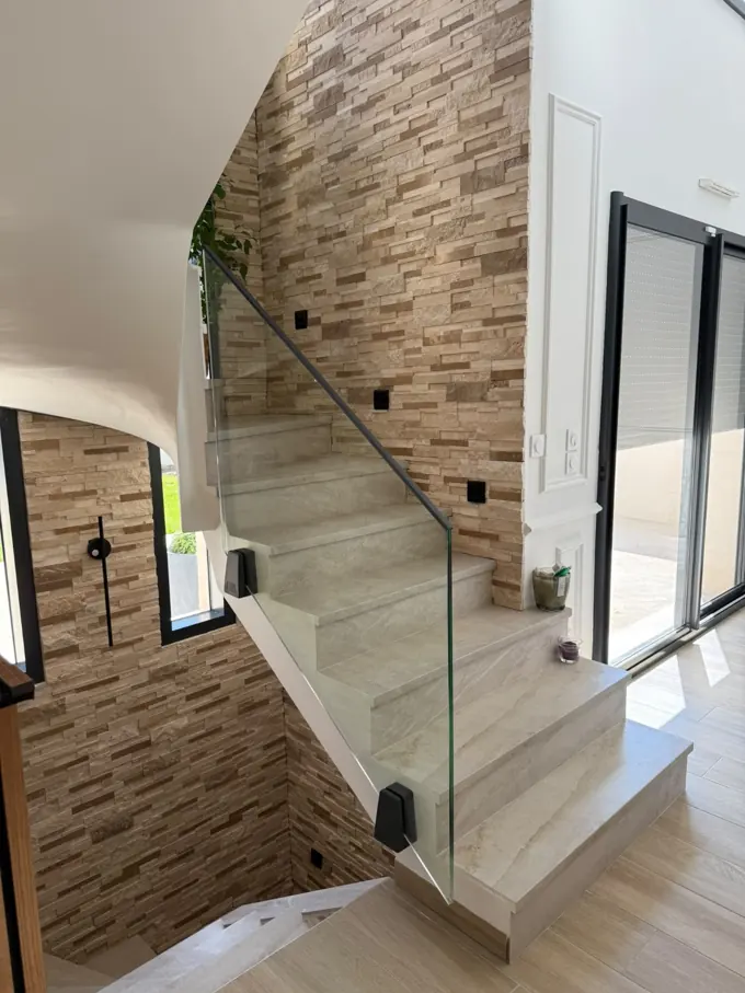 Escalier contemporain vitré sur mur de pierre et intérieur lumineux